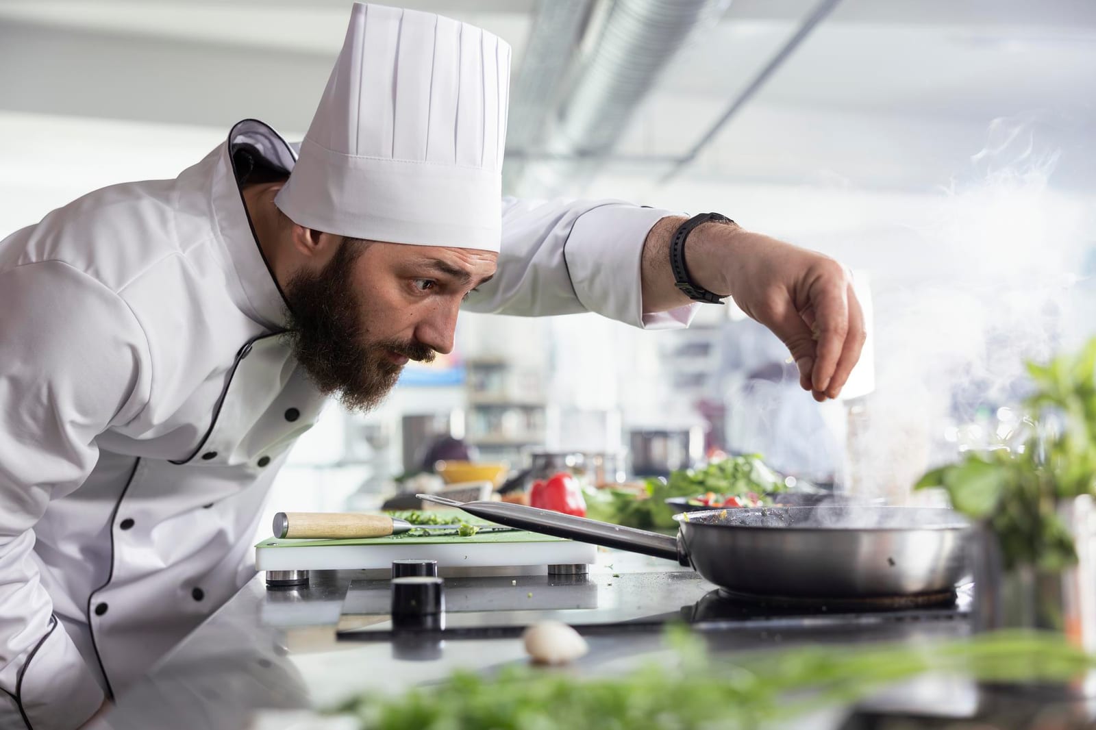 Chef de uniforme branco finalizando um prato com ervas